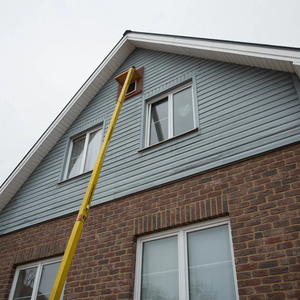 Exterior ladder positioned for an inspection near a roofline vent